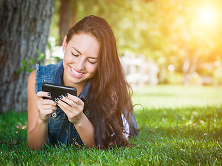 Image showing Mixed Race Young Female Texting on Cell Phone Outside In The Gra