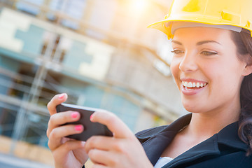 Image showing Female Contractor Wearing Hard Hat on Site Texting with Cell Pho