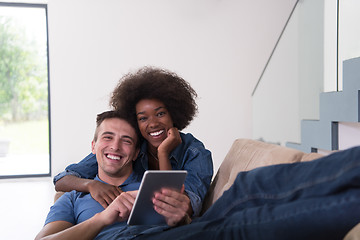 Image showing multiethnic couple relaxing at  home with tablet computers