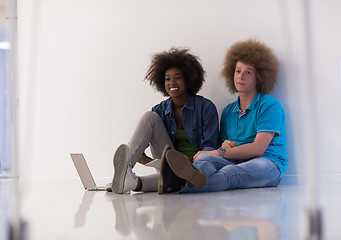 Image showing multiethnic couple sitting on the floor with a laptop and tablet