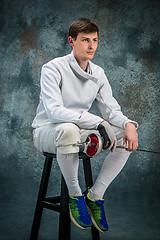 Image showing The man wearing fencing suit with sword against gray