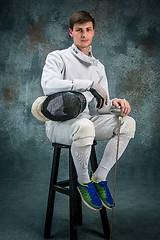 Image showing The man wearing fencing suit with sword against gray