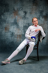 Image showing The woman wearing fencing suit with sword against gray