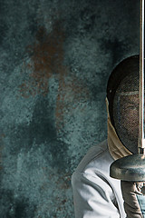 Image showing The man wearing fencing suit with sword against gray