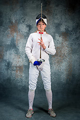 Image showing The woman wearing fencing suit with sword against gray