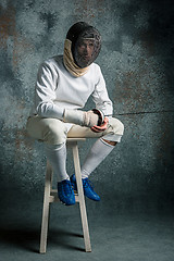 Image showing The man wearing fencing suit with sword against gray