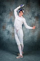 Image showing The woman wearing fencing suit with sword against gray