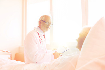 Image showing senior woman and doctor with clipboard at hospital