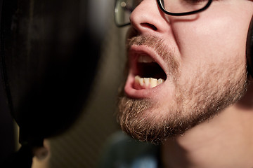 Image showing man with headphones singing at recording studio