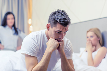 Image showing man sitting on the bed with two women on the back