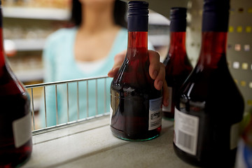 Image showing hand taking bottle of vinegar from shelf at shop