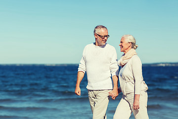 Image showing happy senior couple holding hands on summer beach