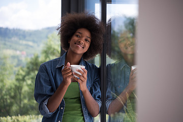 Image showing African American woman drinking coffee looking out the window