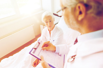 Image showing senior woman and doctor with clipboard at hospital