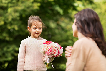 Image showing girl giving with flowers to mother in summer park
