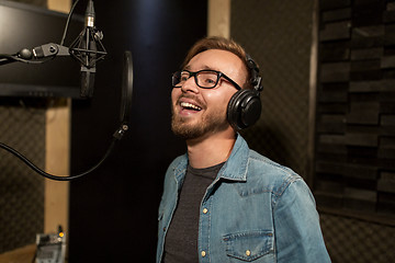 Image showing man with headphones singing at recording studio