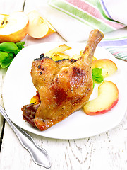 Image showing Duck leg with apple in plate on light board