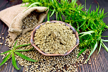 Image showing Flour hemp in bowl with grain in bag on dark board