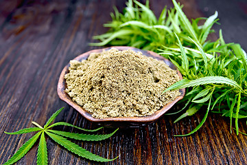 Image showing Flour hemp in clay bowl with leaf on dark board