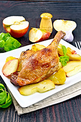 Image showing Duck leg with apple and potatoes on dark board