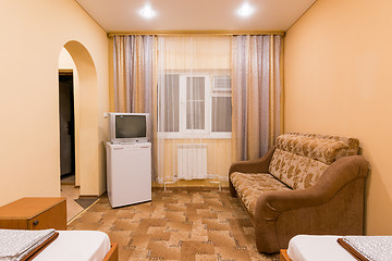 Image showing The interior of a small room with sofa bed and two single beds, window, TV and fridge