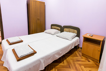 Image showing The interior of a small room with a double bed, a bedside table and wardrobe