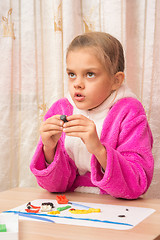 Image showing Seven-year girl looked up thoughtfully engaged in modeling of plasticine