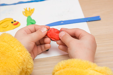 Image showing The child is holding a piece of red clay, close-up