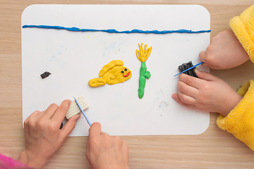 Image showing Page Online Two children are molded from clay on board fish and underwater flower in the sea, the top view