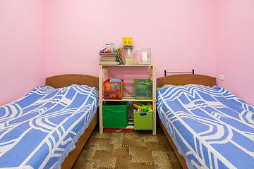 Image showing The interior of a small dorm room with two beds and a homemade rack in the middle