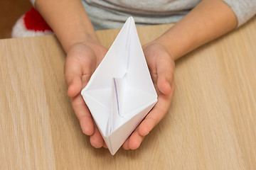 Image showing The child holds in his hands a paper boat