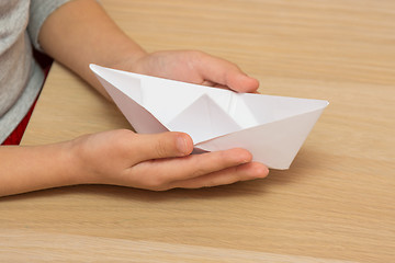 Image showing The child holds in his hands a paper boat, close-up