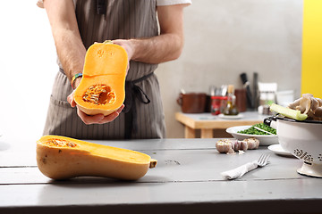 Image showing The cook holds in his hands half a pumpkin. 