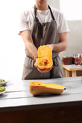 Image showing The cook holds in his hands half a pumpkin. 