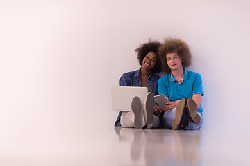 Image showing multiethnic couple sitting on the floor with a laptop and tablet