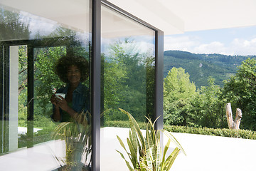 Image showing African American woman drinking coffee looking out the window