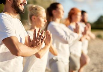 Image showing group of people making yoga or meditating on beach