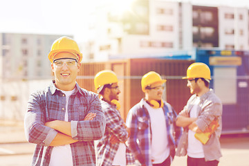 Image showing group of smiling builders in hardhats outdoors