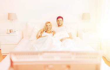 Image showing happy couple lying in bed at home and watching tv