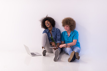 Image showing multiethnic couple sitting on the floor with a laptop and tablet