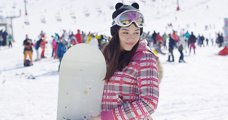 Image showing Smiling woman on ski slope with snowboard