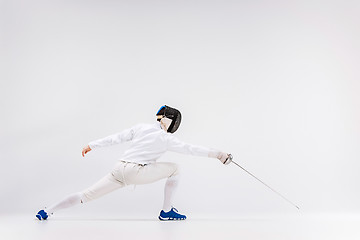 Image showing Man wearing fencing suit practicing with sword against gray