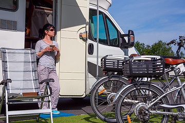 Image showing Woman is standing with a mug of coffee near the camper.