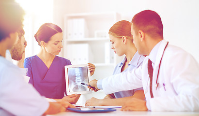 Image showing group of doctors with x-ray on tablet pc at clinic