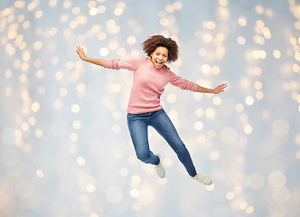 Image showing happy african american woman jumping over white