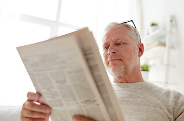 Image showing close up of senior man reading newspaper at home