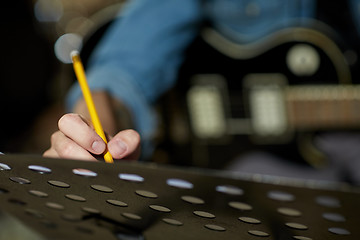 Image showing man with guitar writing to music book at studio