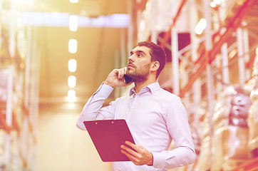Image showing man with clipboard and smartphone at warehouse