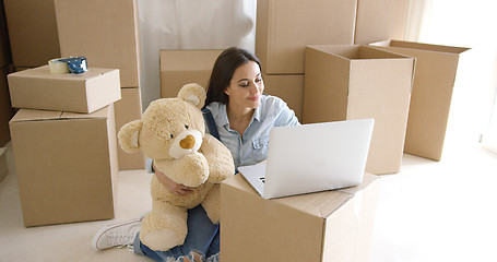 Image showing Young woman moving house with her teddy bear