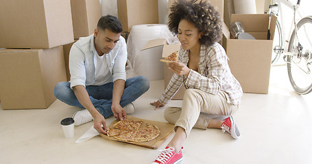 Image showing Young African American couple tucking into a pizza